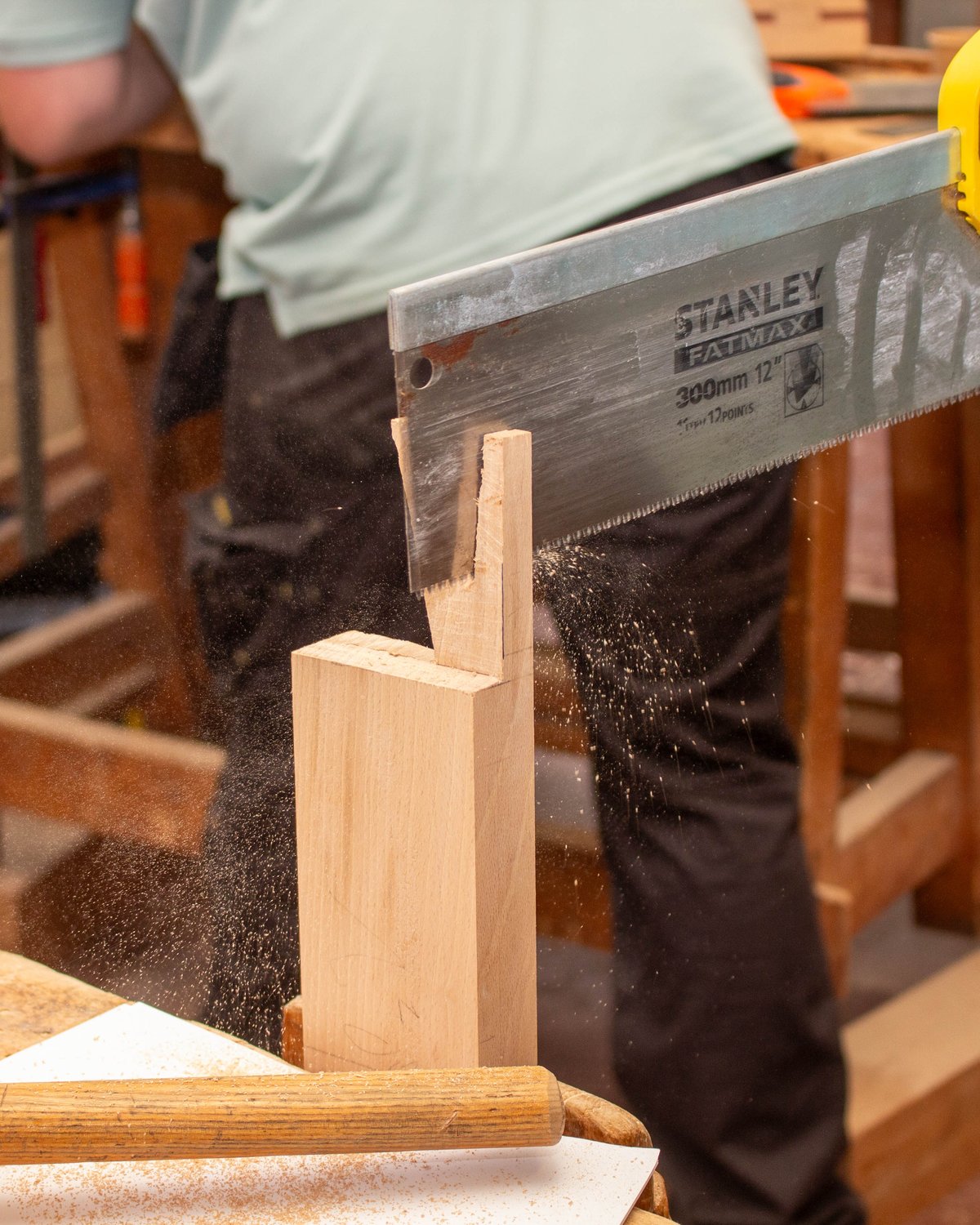 Une scie à dos coupe un tenon dans une pièce de hêtre, à l’atelier de menuiserie