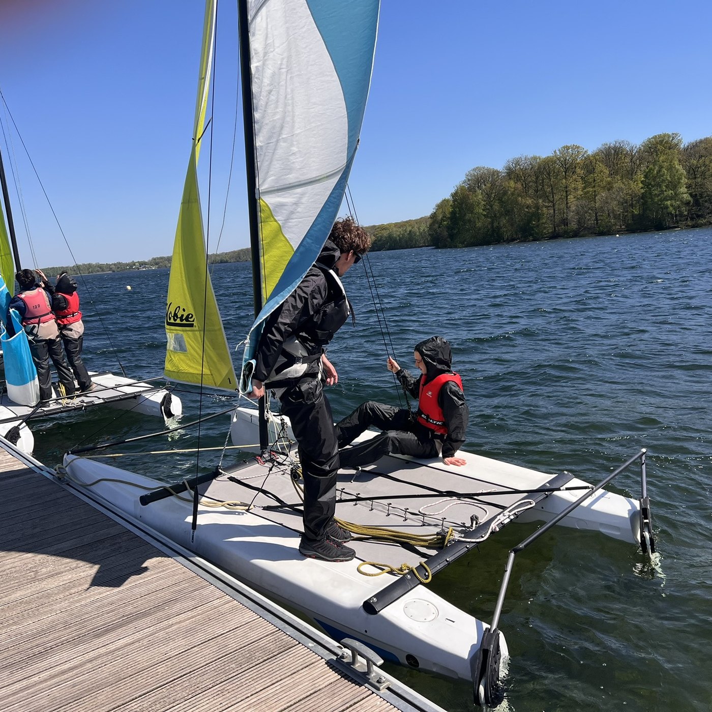 Élèves préparant un catamaran amarré au ponton pendant le stage de voile