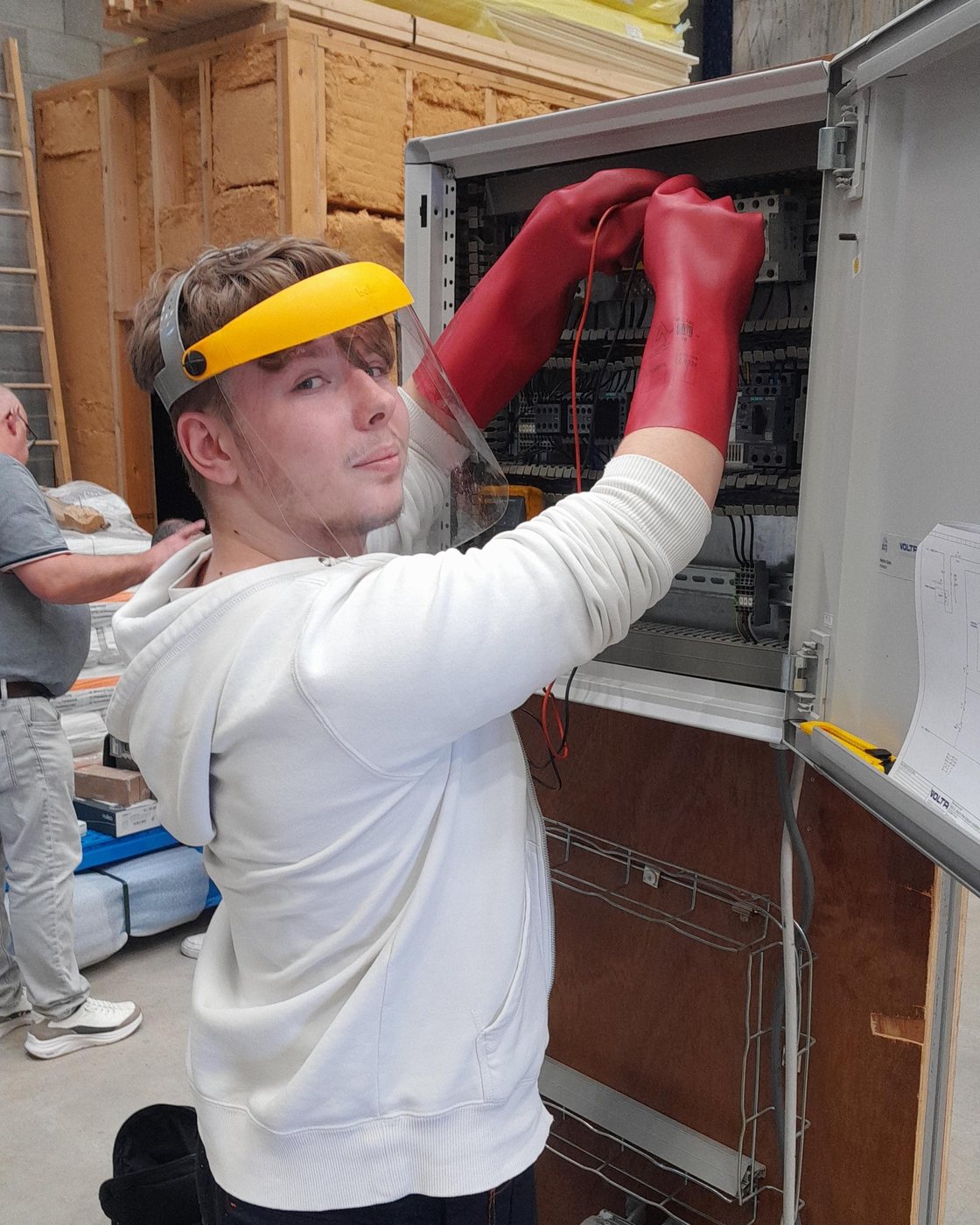 Élève équipé de ses protections travaillant dans une armoire électrique