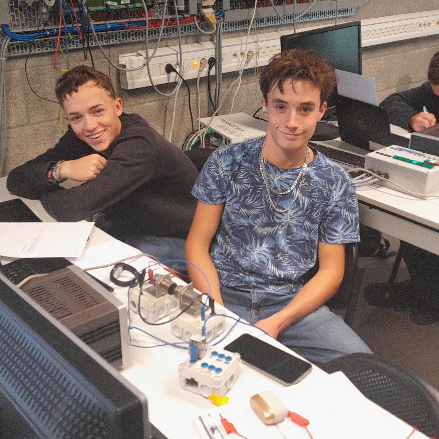 Deux élèves souriants à leur poste de programmation