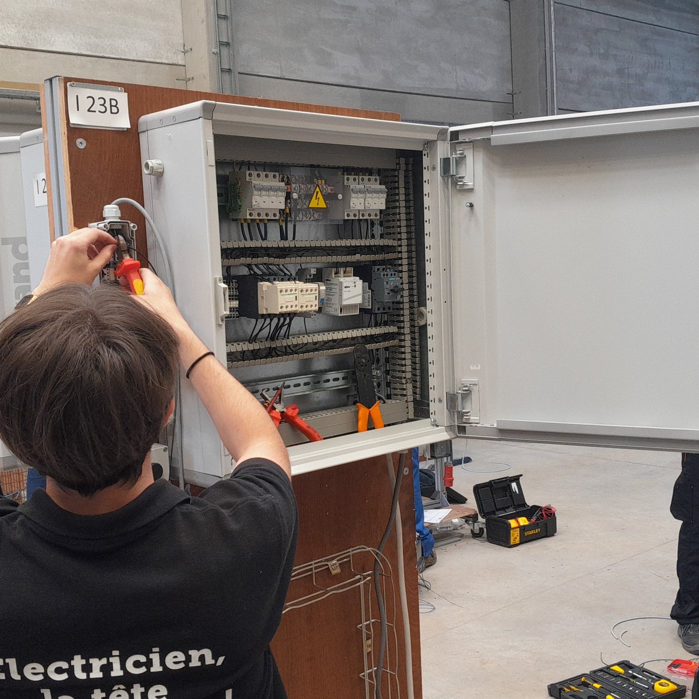 Élève de dos travaillant dans une armoire électrique