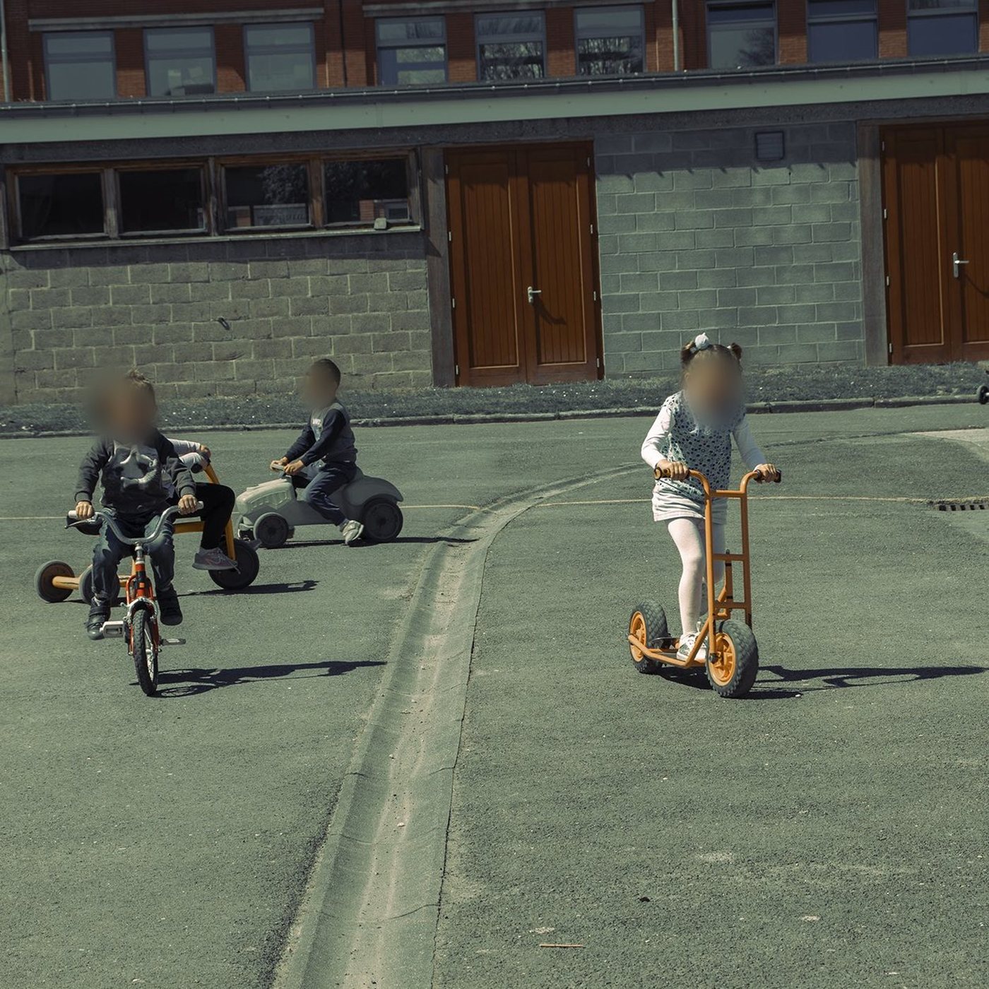 Enfants de maternelle à vélo et à trottinette dans la cour