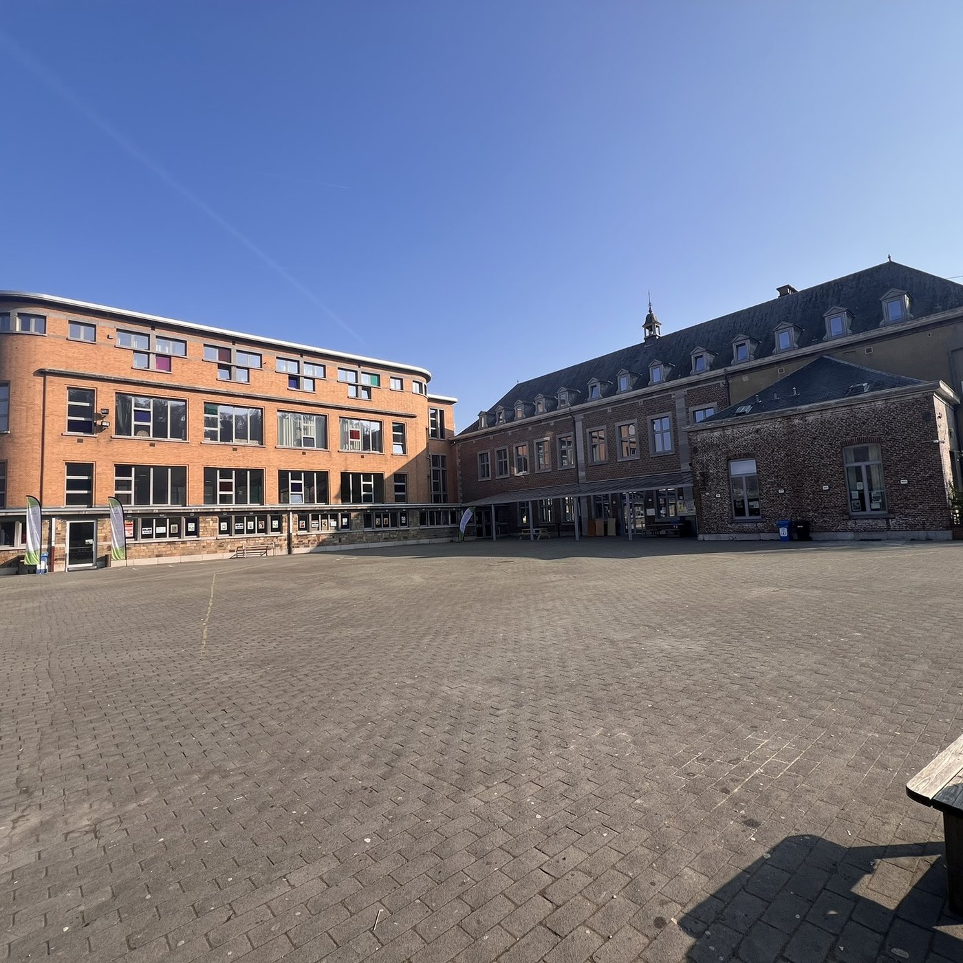 La cour pavée du campus de Huy, entre le bâtiment orange et l’ancienne abbaye