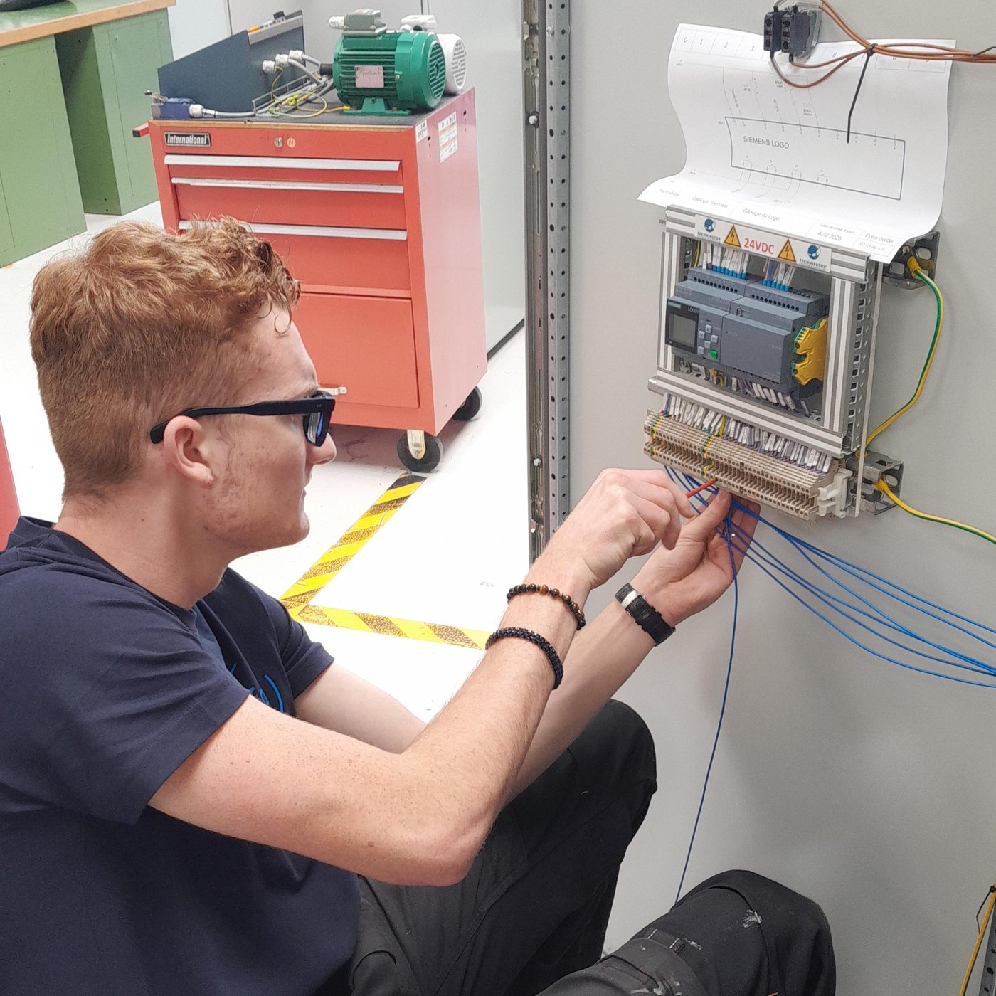 Élève câblant un automate dans une armoire électrique
