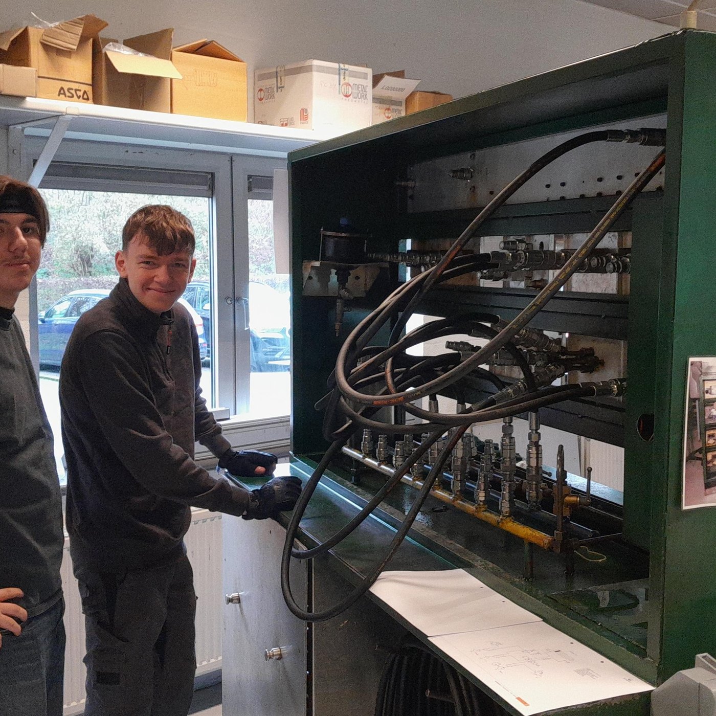 Deux élèves souriants devant un banc hydraulique