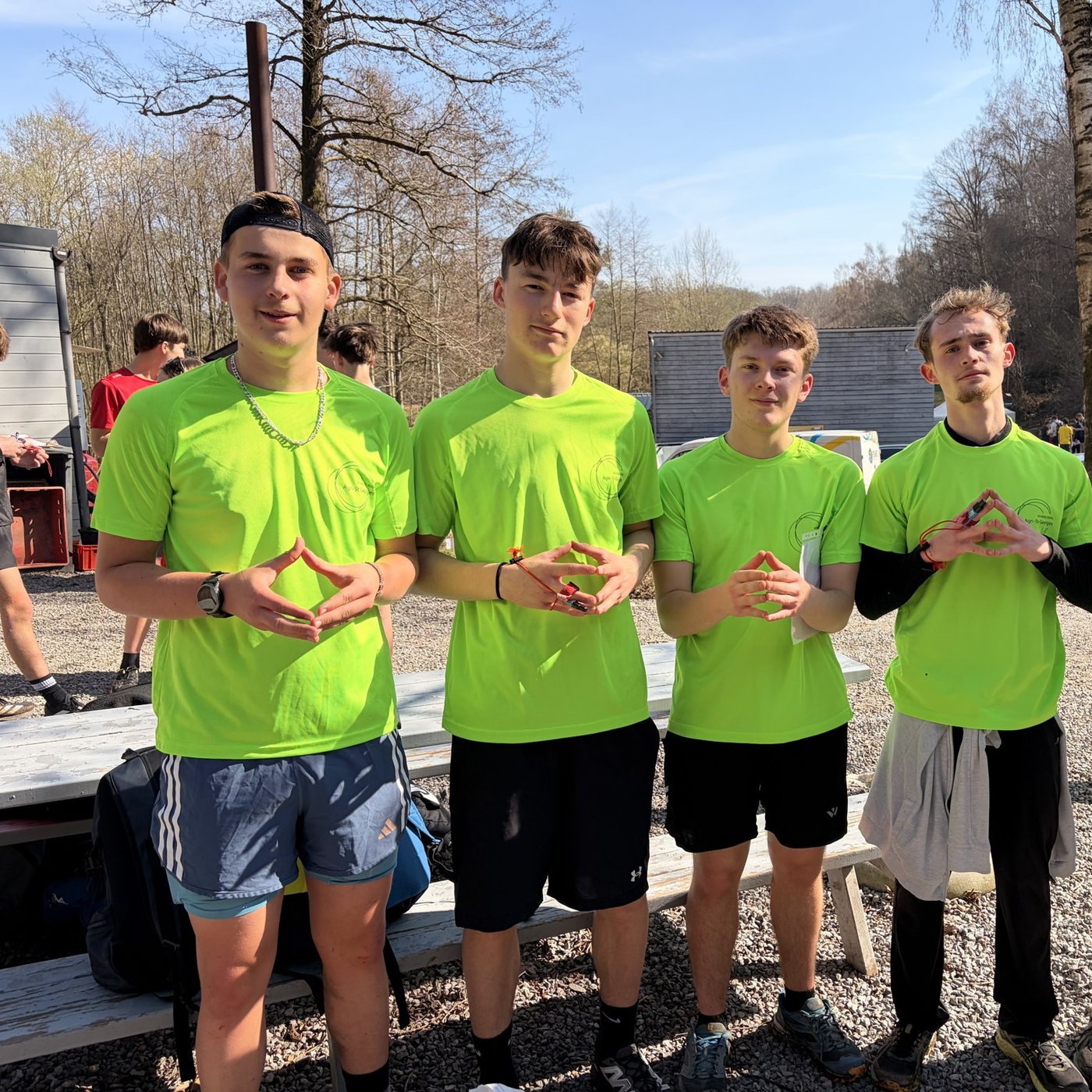 Cinq élèves en t-shirt vert font un cœur avec les mains après une course d’orientation