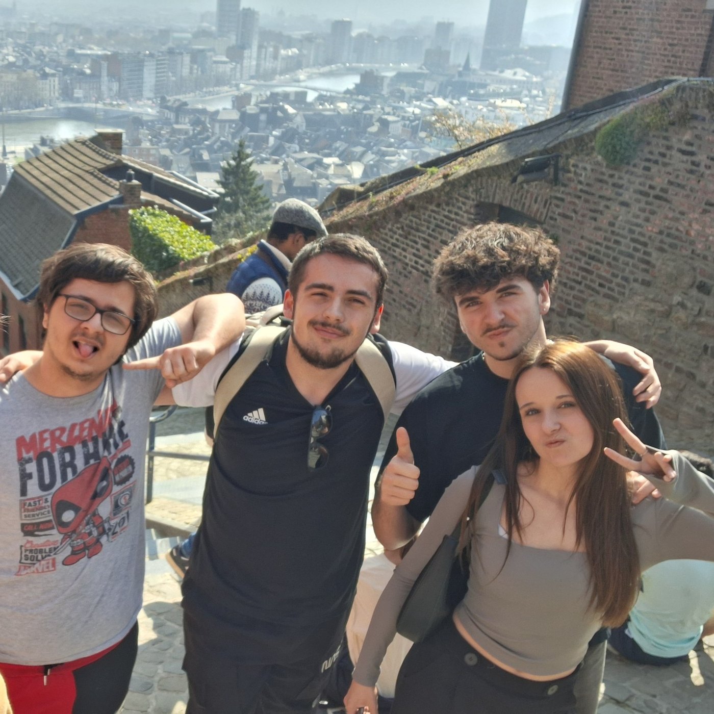 Quatre élèves en haut d’un escalier avec vue sur Liège pendant le rallye photo