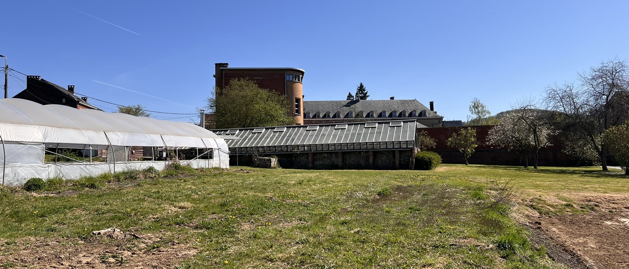 Serres et prairie du campus de Huy, l’abbaye en arrière-plan