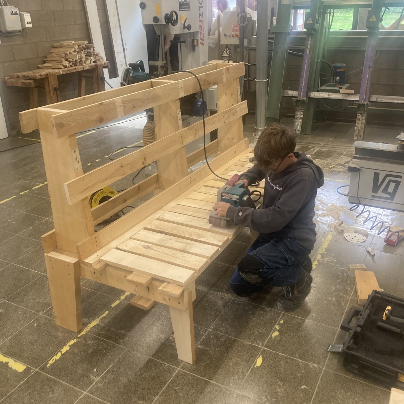 Élève ponçant un banc en bois réalisé à l’atelier pour l’internat